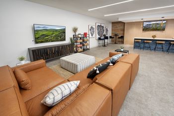 A living room with a brown leather couch and a television on the wall.